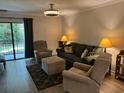 A furnished living room includes a sliding glass door, a sofa, two chairs, and an ottoman at 5001 Little River Rd. # W101, Myrtle Beach, SC 29577