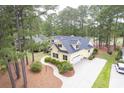 Aerial view of yellow home with spacious driveway, mature landscaping, and a wooded surrounding at 786 Wild Oak Ln. Nw, Calabash, NC 28467