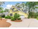 Bright yellow house featuring a large driveway, side entry garage and lush green landscaping at 786 Wild Oak Ln. Nw, Calabash, NC 28467