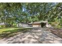 Well maintained house with a large front yard and driveway surrounded by big trees, some of which cast shadows at 103 Wofford Ln., Conway, SC 29526