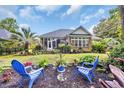 Well-manicured backyard featuring outdoor seating, lush landscaping, and a screened-in porch at 139 Olde Canal Loop, Pawleys Island, SC 29585