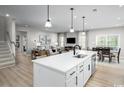 Open-concept kitchen featuring a large island with seating, stainless steel appliances, and views of the living and dining areas at 1408 Whistling Straits Way, Sunset Beach, NC 28468