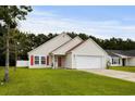 Welcoming single-Gathering home featuring an attached garage, lush lawn, and eye-catching red door and shutters at 221 Tibton Circle, Myrtle Beach, SC 29588