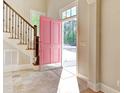 Welcoming foyer with stone tile flooring, a pink front door, and a staircase with decorative iron railings at 55 Pineberry Dr., Georgetown, SC 29440