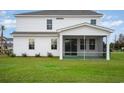 Back of a white house with a screened-in porch overlooking a large grass lawn at 7147 Shooting Star Way, Myrtle Beach, SC 29579