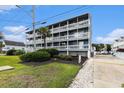 Exterior of a multifamily building featuring grassy lawn, landscaping, and asphalt parking lot at 1210 N Ocean Blvd. # 104, Surfside Beach, SC 29575