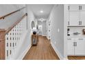 Inviting hallway with wood floors, white trim, and a view of a vanity with round mirror at 1216 Newell Dr, Myrtle Beach, SC 29588