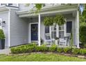 Cozy front porch featuring rocking chairs, hanging ferns, and well-maintained landscaping at 185 Rocko Dr., Myrtle Beach, SC 29579