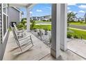 Inviting covered front porch with two rocking chairs, landscaping, and views of the neighborhood street at 1898 Moonseed Dr., Longs, SC 29568