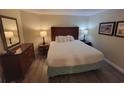 Cozy bedroom with wood-look floors, a queen bed, a dresser, and a nightstand at 201 S Ocean Blvd. # 205, Myrtle Beach, SC 29577