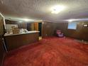Open living room featuring red carpet, wood-paneled walls, and a small kitchen counter at 331 Dixon St., Mullins, SC 29574
