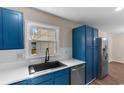 Close-up showcasing the modern kitchen's blue cabinetry, stainless steel dishwasher, and black faucet at 704 Bonnie Dr., Myrtle Beach, SC 29588