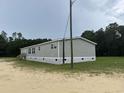 Charming gray mobile home surrounded by grass and trees with a symmetrical window design at 71 Mohican Dr., Georgetown, SC 29440