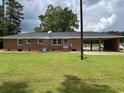 Back view of brick home featuring a carport and large yard at 189 Lewis Rd., Hemingway, SC 29554