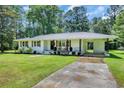 Charming single-story white brick home featuring a well-manicured lawn, driveway and cozy front porch at 265 Powell Loop, Andrews, SC 29510