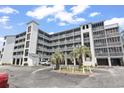 Exterior view of condo building with balconies, palm trees, and parking area at 305 Hillside Dr. N # 205, North Myrtle Beach, SC 29582