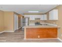 Open concept kitchen with stainless steel refrigerator, white cabinets, island, and wood-look floors at 3700 Golf Colony Lane # 25-D, Little River, SC 29566
