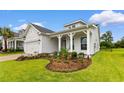 Beautiful white home with meticulously landscaped front yard and inviting covered porch and a view of the garage at 908 Pelagic Loop, Myrtle Beach, SC 29579