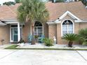 Close up of brick home entrance and manicured landscaping with Adirondack chairs and decorative lawn ornaments at 9614 Indigo Creek Blvd., Murrells Inlet, SC 29576