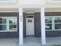 A close-up of the front door, showing the brick facade, white pillars, and windows at 982 Oak Hollow St., Longs, SC 29568