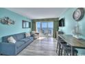 Bright living room with blue sofa, balcony access, and ocean view from the table with bar stools at 2000 N Ocean Blvd. # 1209, Myrtle Beach, SC 29577