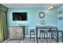 Cozy living space with a TV, retro decor, bar stools, and blue walls providing a relaxed environment at 2000 N Ocean Blvd. # 1209, Myrtle Beach, SC 29577