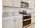 Modern kitchen with white cabinets, granite countertops, and stainless steel appliances including range and microwave at 211 Seasons Trace Loop, Longs, SC 29568