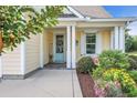Inviting front porch with a light blue door, complemented by lush landscaping and vibrant flowers at 2336 Tidewatch Way, North Myrtle Beach, SC 29582