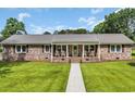 Inviting brick home featuring a covered front porch with rocking chairs and a lush green lawn at 312 S Poplar Ave., Andrews, SC 29510