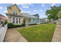 Street view showing the manicured lawn and sidewalk leading to a yellow home with inviting curb appeal at 721 Mckinley Way, Myrtle Beach, SC 29577