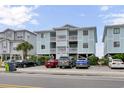 Three-story condo building featuring balconies, light blue siding, and parking underneath the building at 101 W First St. # A2, Ocean Isle Beach, NC 28469