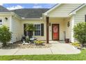 Inviting covered front porch with an orange front door, complemented by a well-maintained landscaped garden at 131 River Country Dr., Conway, SC 29526