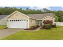 A well-kept single-story home featuring a garage, manicured lawn, and lush green surroundings at 195 Black Pepper Loop, Little River, SC 29566