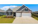 Attractive exterior showcasing a well-maintained lawn, brick accents, and a spacious two-car garage enhancing the home's curb appeal at 215 Kendrick St., Little River, SC 29566