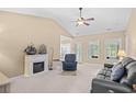 Bright living room featuring a vaulted ceiling, a ceiling fan, and an electric fireplace, with door to the backyard at 4554 Fringetree Dr., Murrells Inlet, SC 29576