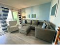Comfortable living room featuring a large grey sectional sofa, accent chair, and sliding door to a balcony at 920 N Waccamaw Dr. # 2206, Garden City Beach, SC 29576
