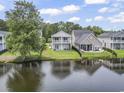 Exterior view of a backyard with a lake, green grass, black fence, and patio furniture on the covered porch at 1048 Meadowoods Dr., Murrells Inlet, SC 29576