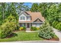 Charming two-story home featuring stone accents, a well-manicured lawn, and mature landscaping at 128 Knotty Pine Way, Murrells Inlet, SC 29576