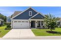 Attractive home featuring blue and tan siding, a well-kept lawn, and a decorative tree, enhancing its outdoor charm at 264 Switchgrass Loop, Little River, SC 29566