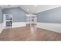 Spacious open-concept living room with blue walls, white wainscoting, and wood-look flooring at 307 Russ Rd., Loris, SC 29569