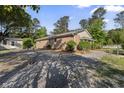 A view of the brick house exterior with gravel landscaping and mature trees at 3269 Sims Rd., Marion, SC 29571