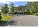 Wide gravel driveway leads to a well-maintained home with lush, mature trees at 3269 Sims Rd., Marion, SC 29571