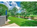 Serene backyard featuring a pond view, mature trees, and lush landscaping at 456 Colonial Trace Dr. # 13-E, Longs, SC 29568