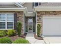 The front of this home features a stone facade and well maintained landscaping around the walkway and door at 5716 Lombardia Circle, Myrtle Beach, SC 29579
