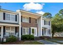 A lovely townhouse with a brick and vinyl exterior, under a blue sky, featuring shaded entrances and a well-kept lawn at 4115 Little River Rd. # 1-E, Myrtle Beach, SC 29577