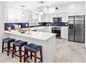 Well-lit kitchen featuring white cabinets, a breakfast bar with blue stools, and stainless steel appliances at 867 Cardinal Pl., North Myrtle Beach, SC 29582