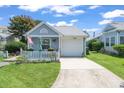Inviting one-story home featuring light blue siding, an attached garage, and a cute front porch with a picket fence at 110 Cambridge Circle, Myrtle Beach, SC 29577