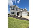 Well-maintained two-story home featuring gray siding, black shutters, landscaped front yard, and an attached garage at 1715 Perthshire Loop, Myrtle Beach, SC 29579