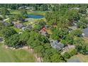 Aerial shot of a brick house nestled in lush greenery with a golf course, pond, and other houses nearby at 3975 River Hills Dr., Little River, SC 29566