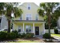 Inviting two-story home with classic columns, a cozy porch, and a beautifully landscaped yard with palm trees at 433 Emerson Dr., Myrtle Beach, SC 29579